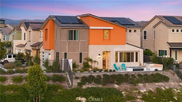 3173 Ivy Way, Rancho Mission Viejo, CA 92694 - back of house at dusk featuring stucco siding, solar panels, a fenced backyard, and a patio area