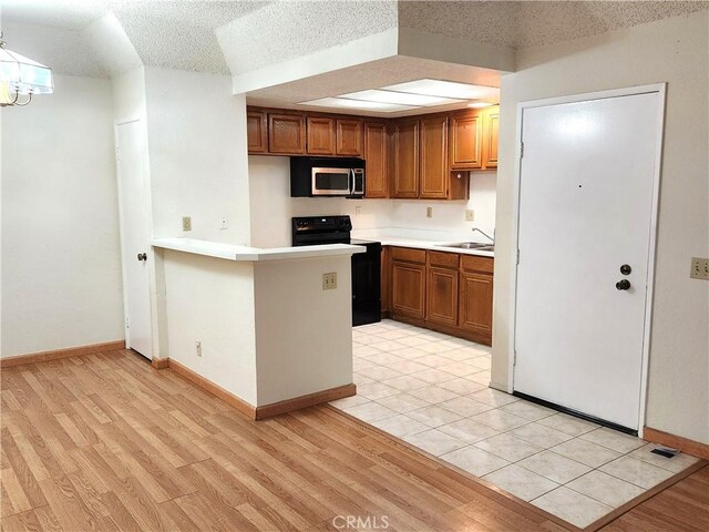 22790 Lakeway Dr Unit 461, Diamond Bar, CA 91765 - kitchen with stainless steel microwave, black range with electric cooktop, brown cabinets, light countertops, and a peninsula