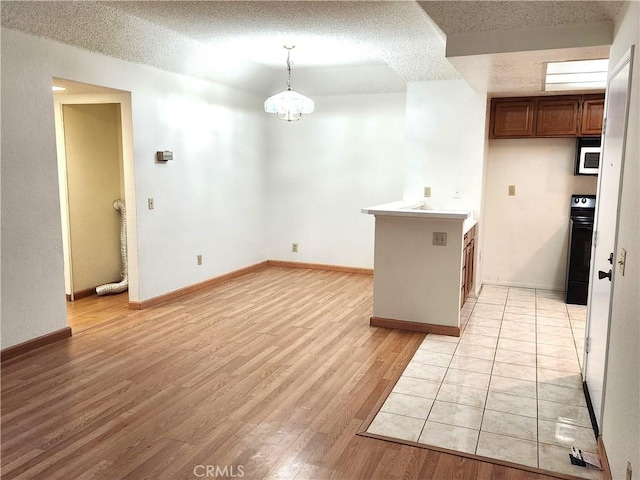 22790 Lakeway Dr Unit 461, Diamond Bar, CA 91765 - kitchen featuring white microwave, light wood-type flooring, a textured ceiling, brown cabinets, and hanging light fixtures