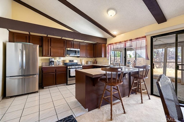 44668 13th St E, Lancaster, CA 93535 - kitchen featuring appliances with stainless steel finishes, a peninsula, a textured ceiling, a breakfast bar, and tile counters