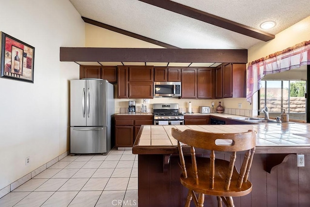 44668 13th St E, Lancaster, CA 93535 - kitchen with stainless steel appliances, tile counters, a peninsula, a breakfast bar area, and a textured ceiling