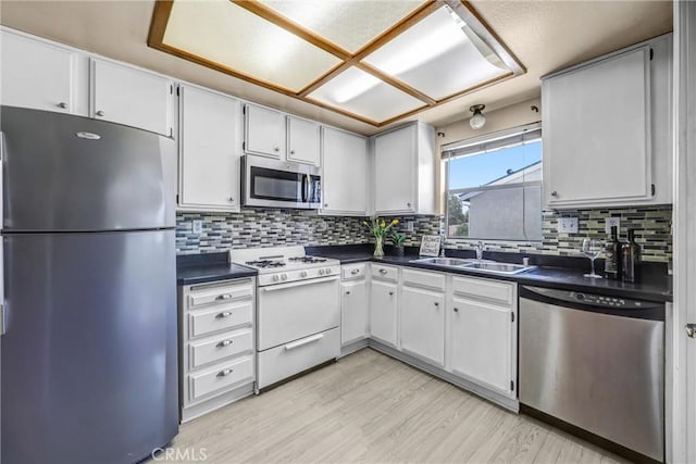 13303 Waco St Unit 32, Baldwin Park, CA 91706 - kitchen with appliances with stainless steel finishes, dark countertops, light wood-style flooring, and tasteful backsplash