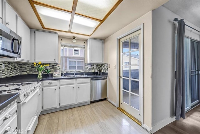 13303 Waco St Unit 32, Baldwin Park, CA 91706 - kitchen featuring stainless steel appliances, dark countertops, light wood finished floors, decorative backsplash, and white cabinets