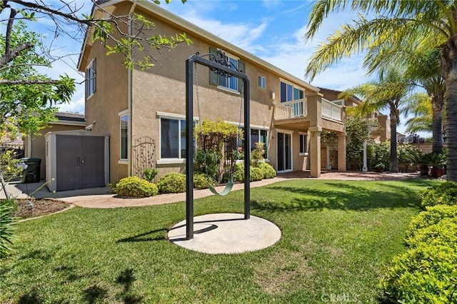 24058 Via Vis, Valencia, CA 91354 - rear view of house featuring stucco siding, a yard, a storage shed, and a balcony