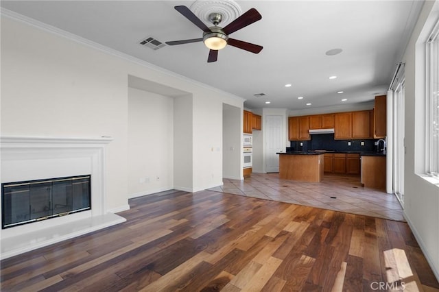 24058 Via Vis, Valencia, CA 91354 - unfurnished living room featuring recessed lighting, a ceiling fan, dark wood-style flooring, crown molding, and a glass covered fireplace
