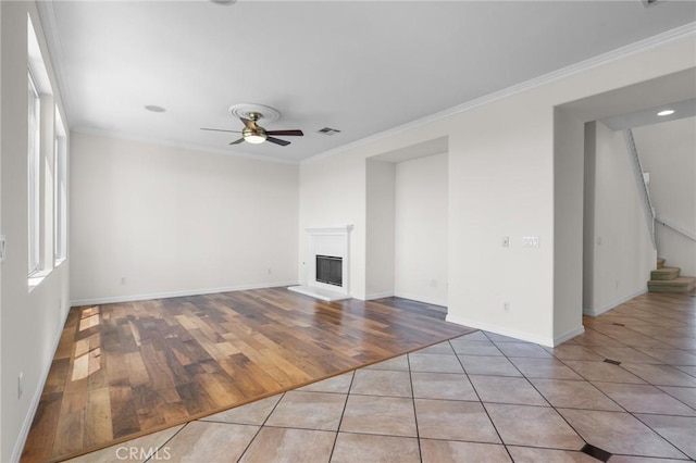 24058 Via Vis, Valencia, CA 91354 - unfurnished living room featuring a ceiling fan, crown molding, a fireplace with raised hearth, plenty of natural light, and stairs