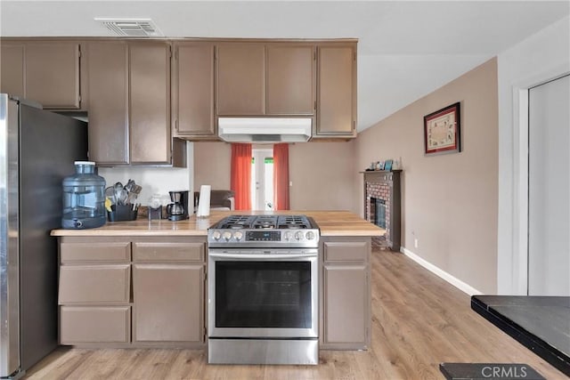 8960 Buckthorn Ave, Hesperia, CA 92345 - kitchen with stainless steel appliances, under cabinet range hood, light countertops, light wood-type flooring, and a brick fireplace