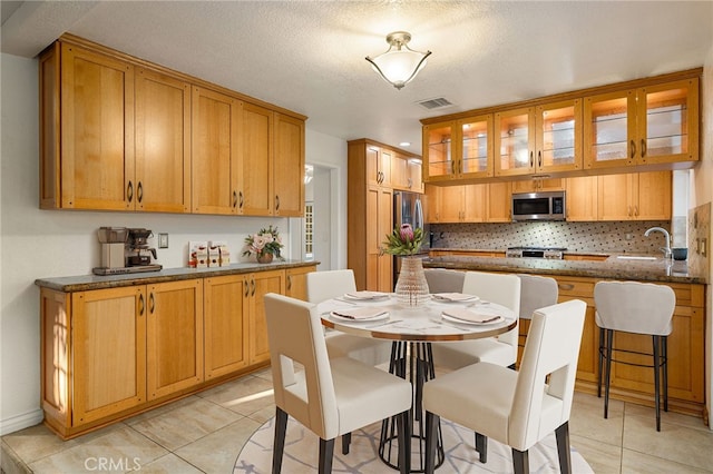 1722 Calle Alto, San Dimas, CA 91773 - kitchen with appliances with stainless steel finishes, light tile patterned floors, decorative backsplash, glass insert cabinets, and dark stone countertops