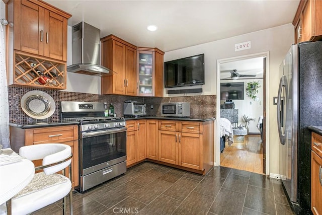 3432 Larissa Dr, Los Angeles, CA 90026 - kitchen featuring stainless steel appliances, wall chimney range hood, tasteful backsplash, brown cabinetry, and recessed lighting
