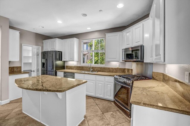13325 Via Tresca Unit 7, San Diego, CA 92129 - kitchen with appliances with stainless steel finishes, a center island, white cabinets, light tile patterned floors, and recessed lighting