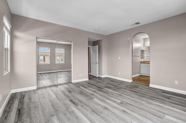 13325 Via Tresca Unit 7, San Diego, CA 92129 - unfurnished bedroom featuring arched walkways, multiple windows, wood finished floors, and a closet