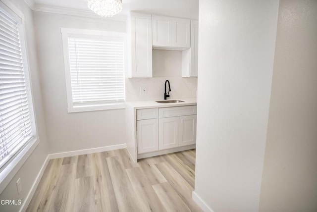 1925 Ginger St Unit 112, Oxnard, CA 93036 - kitchen with a chandelier, light countertops, light wood finished floors, crown molding, and white cabinetry