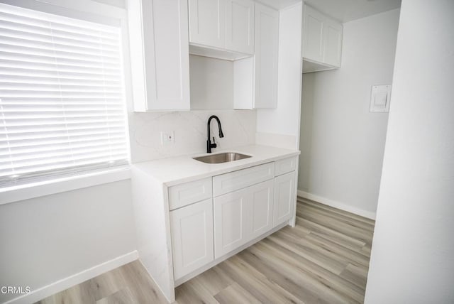 1925 Ginger St Unit 112, Oxnard, CA 93036 - kitchen with white cabinets, light wood finished floors, light countertops, and decorative backsplash