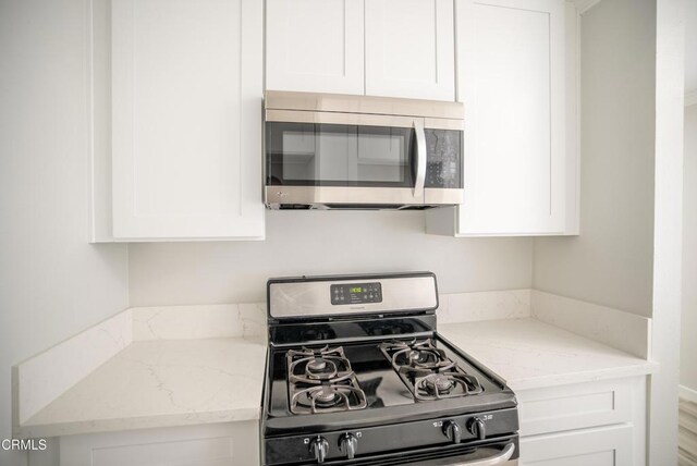 1925 Ginger St Unit 112, Oxnard, CA 93036 - kitchen with range with gas cooktop, stainless steel microwave, white cabinets, and light stone counters