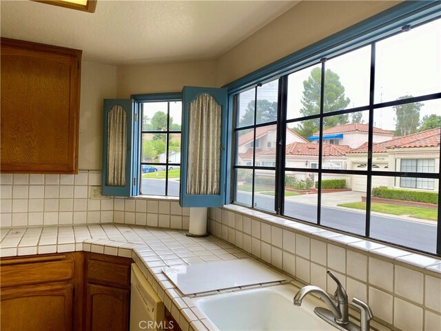 28432 Alava, Mission Viejo, CA 92692 - kitchen featuring tile counters, backsplash, white dishwasher, and brown cabinetry