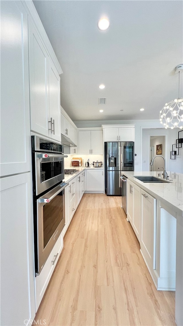 122 Espina, Irvine, CA 92620 - kitchen featuring stainless steel appliances, under cabinet range hood, light wood-type flooring, white cabinets, and recessed lighting