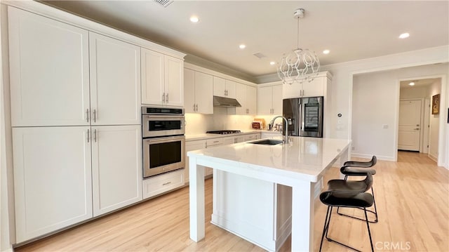 122 Espina, Irvine, CA 92620 - kitchen featuring stainless steel appliances, under cabinet range hood, light wood-style flooring, a kitchen breakfast bar, and recessed lighting