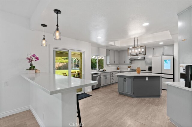 12026 Haven Crest St, Moorpark, CA 93021 - kitchen with gray cabinets, freestanding refrigerator, stainless steel dishwasher, under cabinet range hood, and light countertops