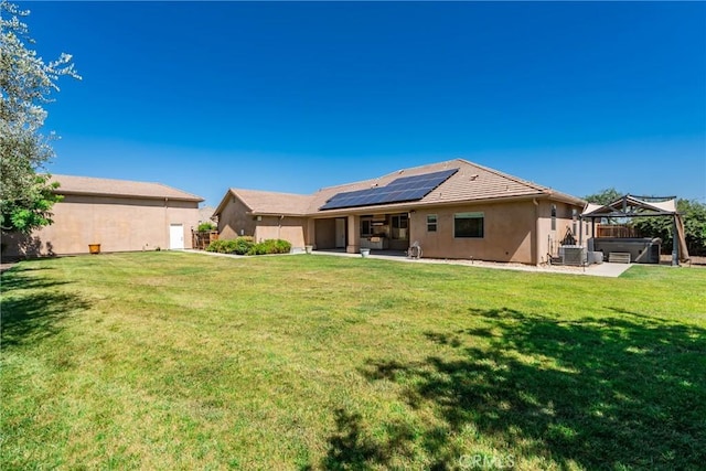 13611 Francisco Dr, Hanford, CA 93230 - rear view of house with a hot tub, a patio area, solar panels, stucco siding, and a lawn