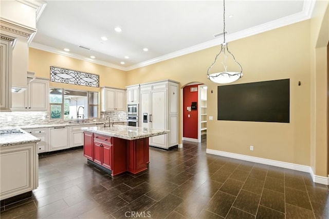 13611 Francisco Dr, Hanford, CA 93230 - kitchen featuring backsplash, arched walkways, appliances with stainless steel finishes, a kitchen island with sink, and ornamental molding