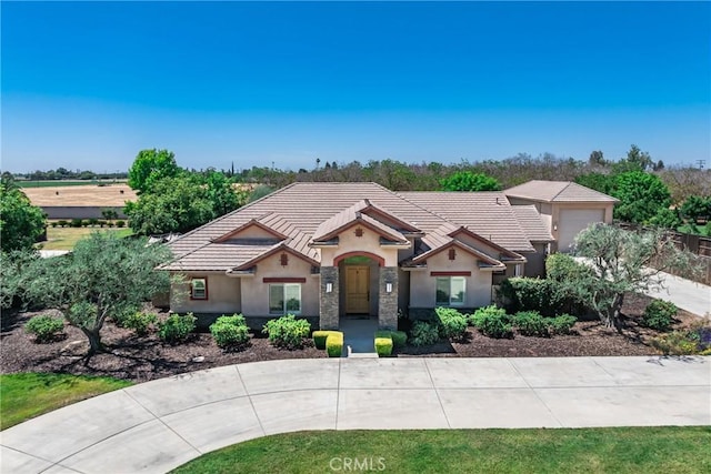 13611 Francisco Dr, Hanford, CA 93230 - view of front of house with stucco siding, a tile roof, stone siding, and curved driveway