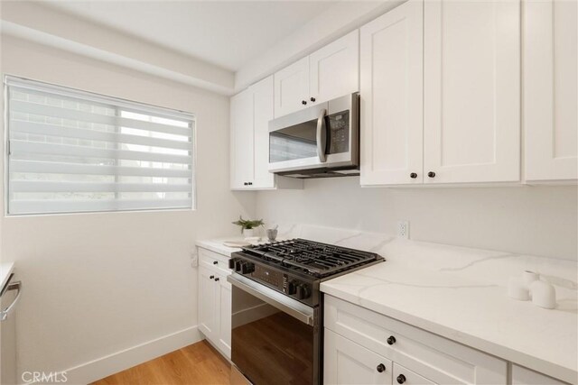 525 E Verdugo Ave Unit E, Burbank, CA 91501 - kitchen with stainless steel microwave, gas range, light wood-type flooring, white cabinets, and light stone countertops