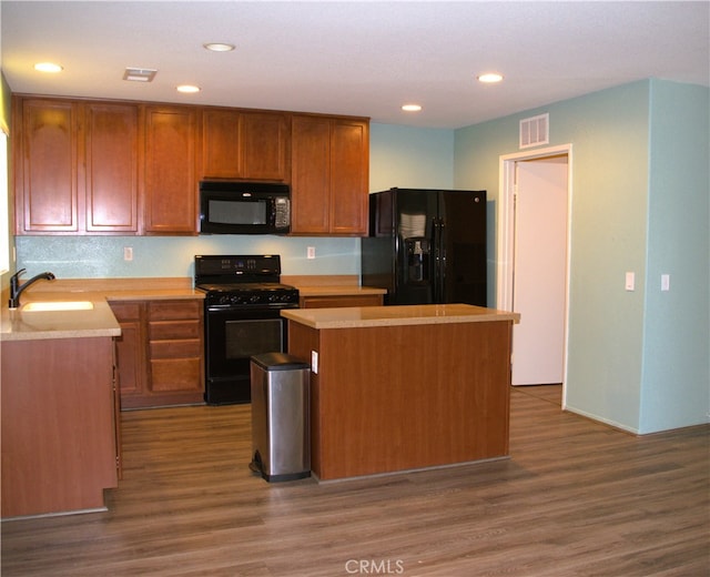 16558 Jasmine St, Victorville, CA 92395 - kitchen featuring black appliances, a center island, light countertops, wood finished floors, and recessed lighting