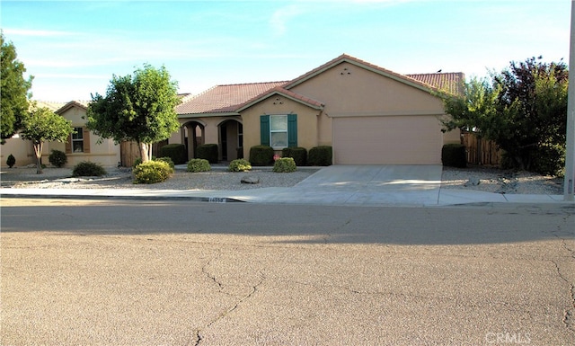 16558 Jasmine St, Victorville, CA 92395 - mediterranean / spanish home featuring a tiled roof, stucco siding, a garage, and driveway