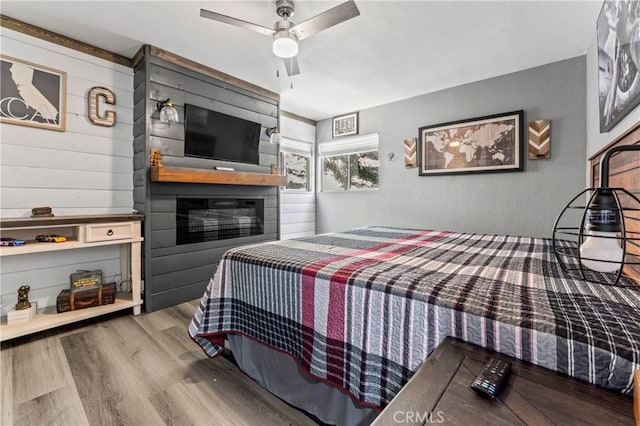 32538 Scandia Dr, Running Springs, CA 92382 - bedroom with wood finished floors, ceiling fan, and a large fireplace