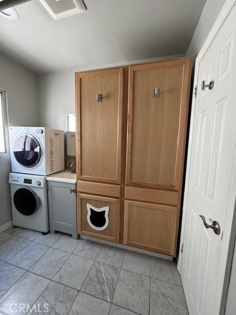 438 Cedar Ave Unit 6, Long Beach, CA 90802 - laundry room with estacked washer and dryer, cabinet space, and light marble finish floors