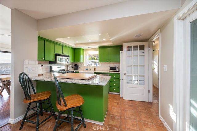 5175 White Tail Pl, Paso Robles, CA 93446 - kitchen featuring green cabinetry, appliances with stainless steel finishes, a raised ceiling, a peninsula, and decorative backsplash