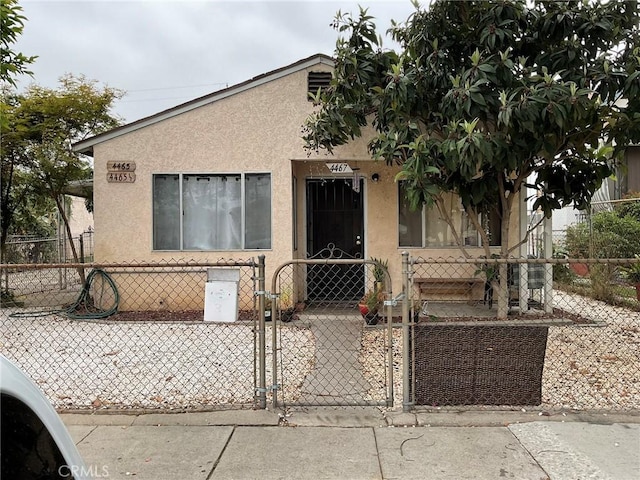 4465 Lovett St, Commerce, CA 90040 - view of front facade featuring stucco siding, a fenced front yard, and a gate
