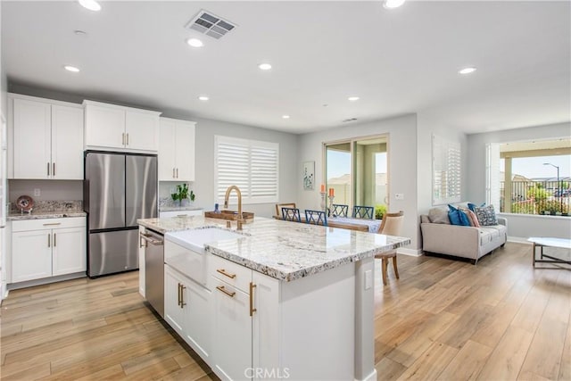1563 Sunswept Way, Beaumont, CA 92223 - kitchen with stainless steel appliances, healthy amount of natural light, light wood-style floors, white cabinetry, and recessed lighting