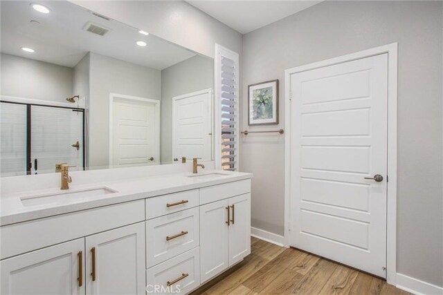 1563 Sunswept Way, Beaumont, CA 92223 - bathroom featuring double vanity, wood finished floors, a shower stall, and recessed lighting
