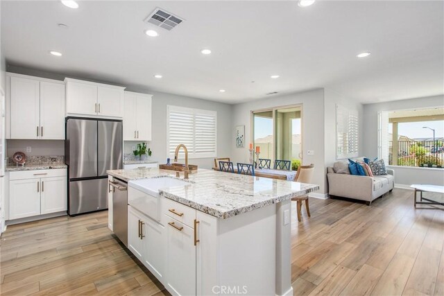 1563 Sunswept Way, Beaumont, CA 92223 - kitchen with stainless steel appliances, healthy amount of natural light, light wood finished floors, white cabinetry, and recessed lighting
