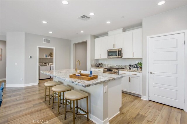 1563 Sunswept Way, Beaumont, CA 92223 - kitchen featuring stainless steel appliances, independent washer and dryer, light wood-style flooring, a center island with sink, and recessed lighting