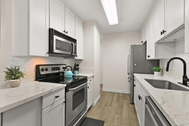 9959 Azuaga St Unit 105, San Diego, CA 92129 - kitchen featuring appliances with stainless steel finishes, decorative backsplash, light wood-style flooring, white cabinets, and light stone countertops