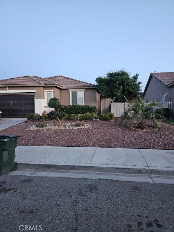 11847 Branch Ct, Adelanto, CA 92301 - view of front of home with an attached garage, driveway, and stucco siding