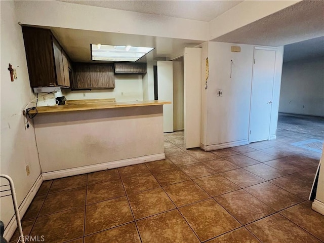 13500 Ramona Pkwy, Baldwin Park, CA 91706 - kitchen featuring tile patterned flooring, a peninsula, dark brown cabinetry, butcher block counters, and a textured ceiling