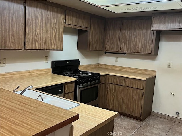 13500 Ramona Pkwy, Baldwin Park, CA 91706 - kitchen with range with gas cooktop, light countertops, light tile patterned floors, and dark brown cabinetry
