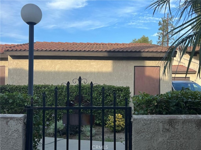 13500 Ramona Pkwy, Baldwin Park, CA 91706 - view of side of property with stucco siding, a tiled roof, and a gate