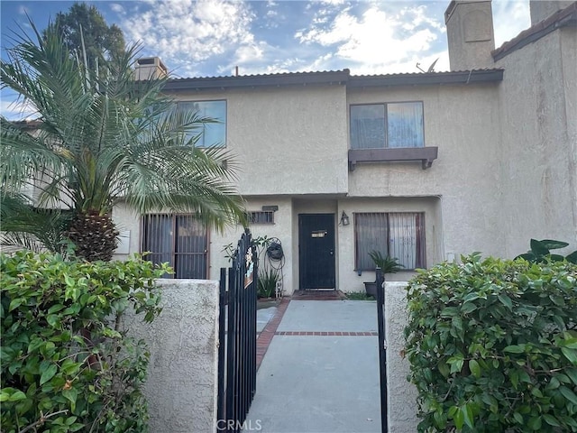 13500 Ramona Pkwy, Baldwin Park, CA 91706 - view of front facade with stucco siding, a chimney, and a gate