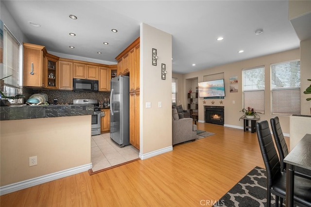 1879 Atlantic Ave Unit 15, Long Beach, CA 90806 - kitchen with appliances with stainless steel finishes, light wood-style flooring, glass insert cabinets, a tiled fireplace, and tile counters