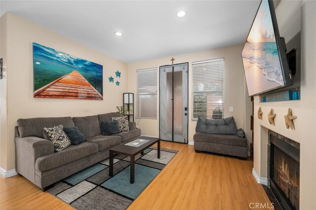 1879 Atlantic Ave Unit 15, Long Beach, CA 90806 - living area with wood finished floors, a lit fireplace, and recessed lighting