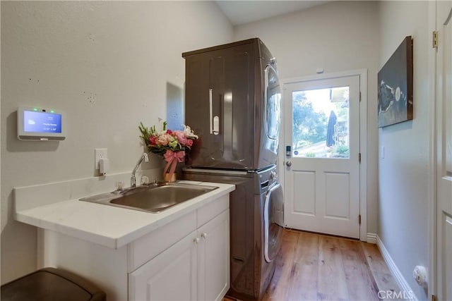 2424 Gird Rd, Fallbrook, CA 92028 - washroom featuring stacked washer / drying machine, light wood finished floors, and cabinet space