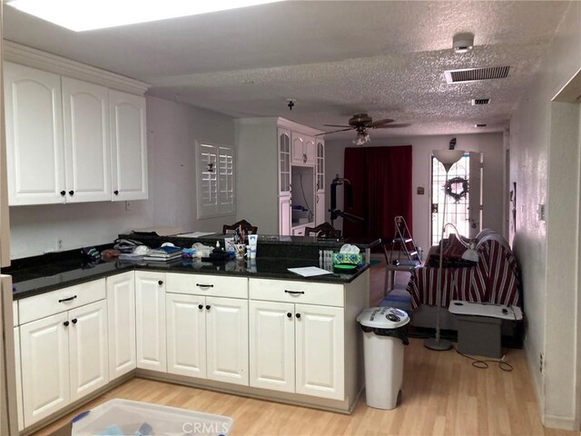 35590 Santa Fe St, Daggett, CA 92327 - kitchen with a peninsula, light wood-type flooring, a textured ceiling, ceiling fan, and white cabinetry