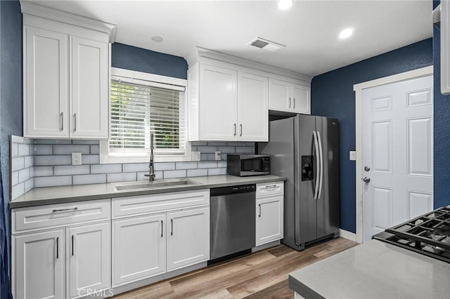 1131 Stewart Ave, Chico, CA 95926 - kitchen featuring appliances with stainless steel finishes, white cabinets, light wood finished floors, backsplash, and light countertops