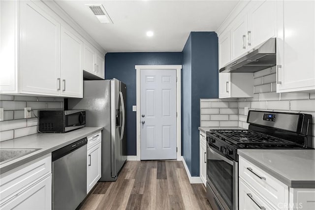 1131 Stewart Ave, Chico, CA 95926 - kitchen featuring appliances with stainless steel finishes, under cabinet range hood, dark wood-style flooring, decorative backsplash, and white cabinets