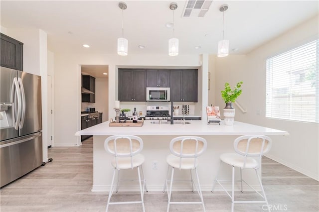1504 Granada Rd, Upland, CA 91786 - kitchen featuring appliances with stainless steel finishes, light wood-style flooring, dark brown cabinets, light countertops, and a kitchen bar
