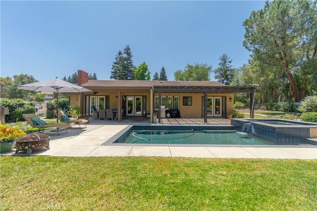 712 Buckingham Dr, Redlands, CA 92374 - rear view of property featuring french doors, an outdoor fire pit, a patio, a pool with connected hot tub, and a chimney